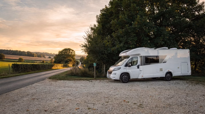 Camping-car blanc moderne stationné paisiblement sur une aire rurale française