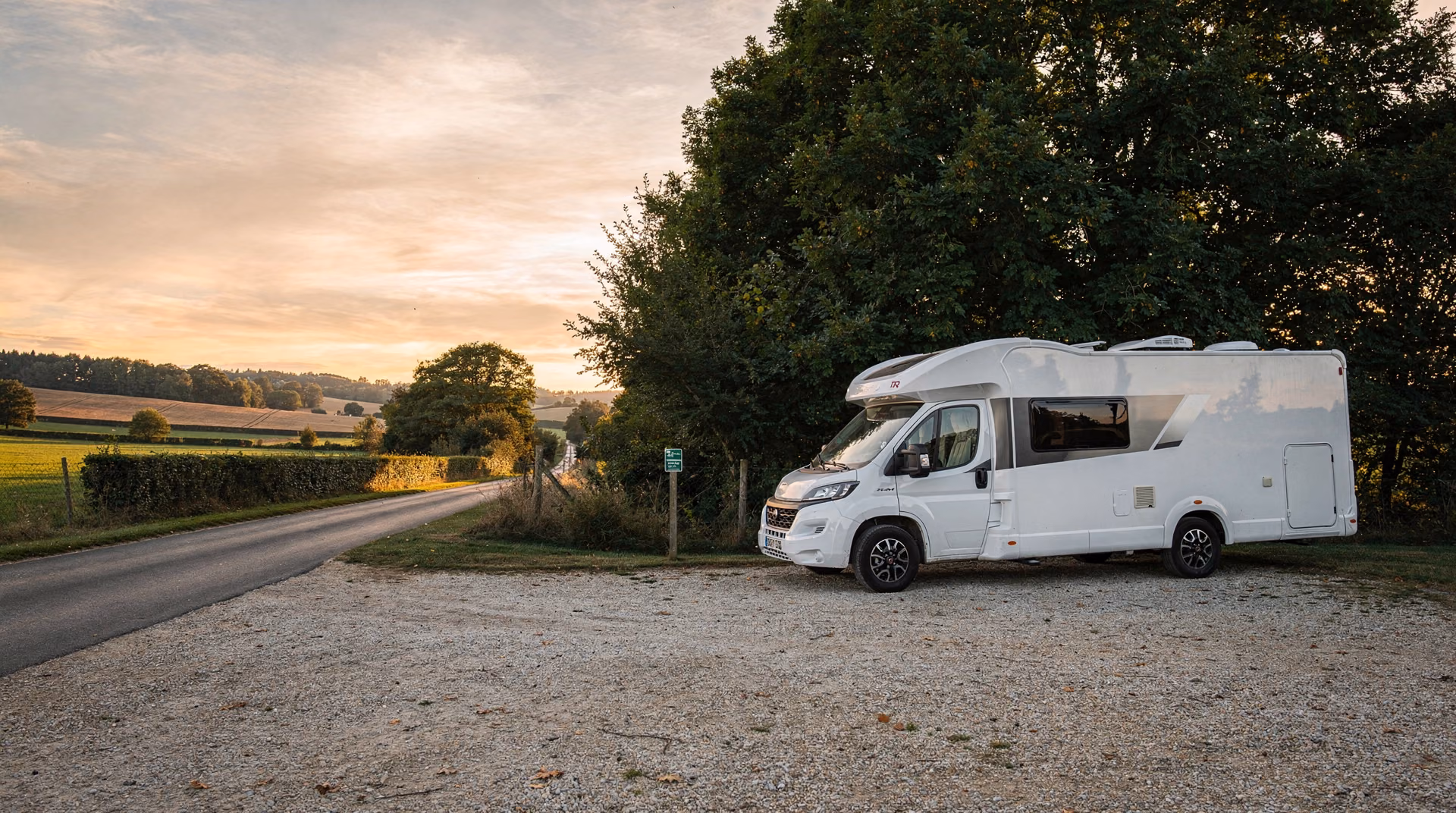 Camping-car blanc moderne stationné paisiblement sur une aire rurale française